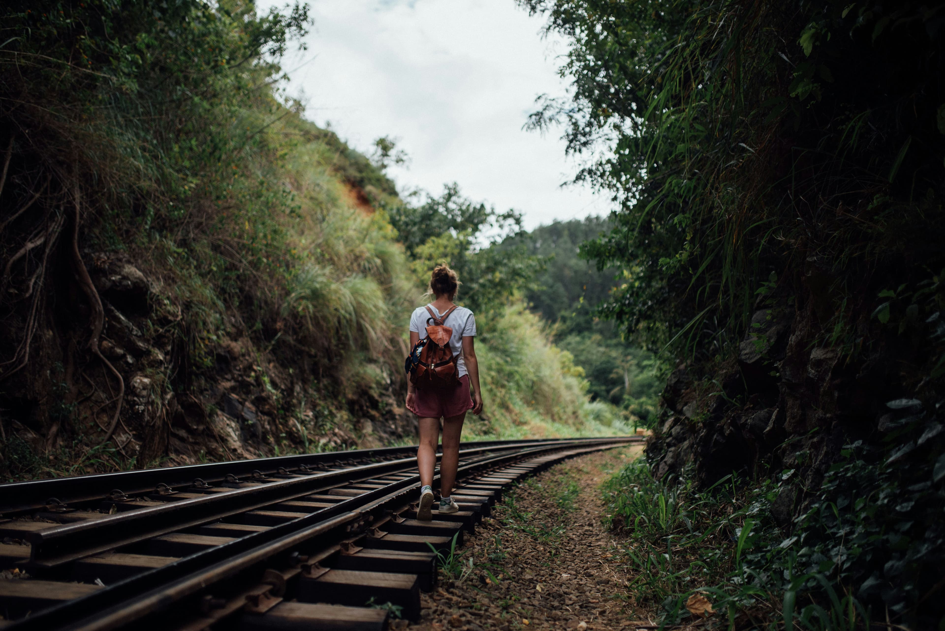 A traveller walking along a railway through Sri Lanka's hill country